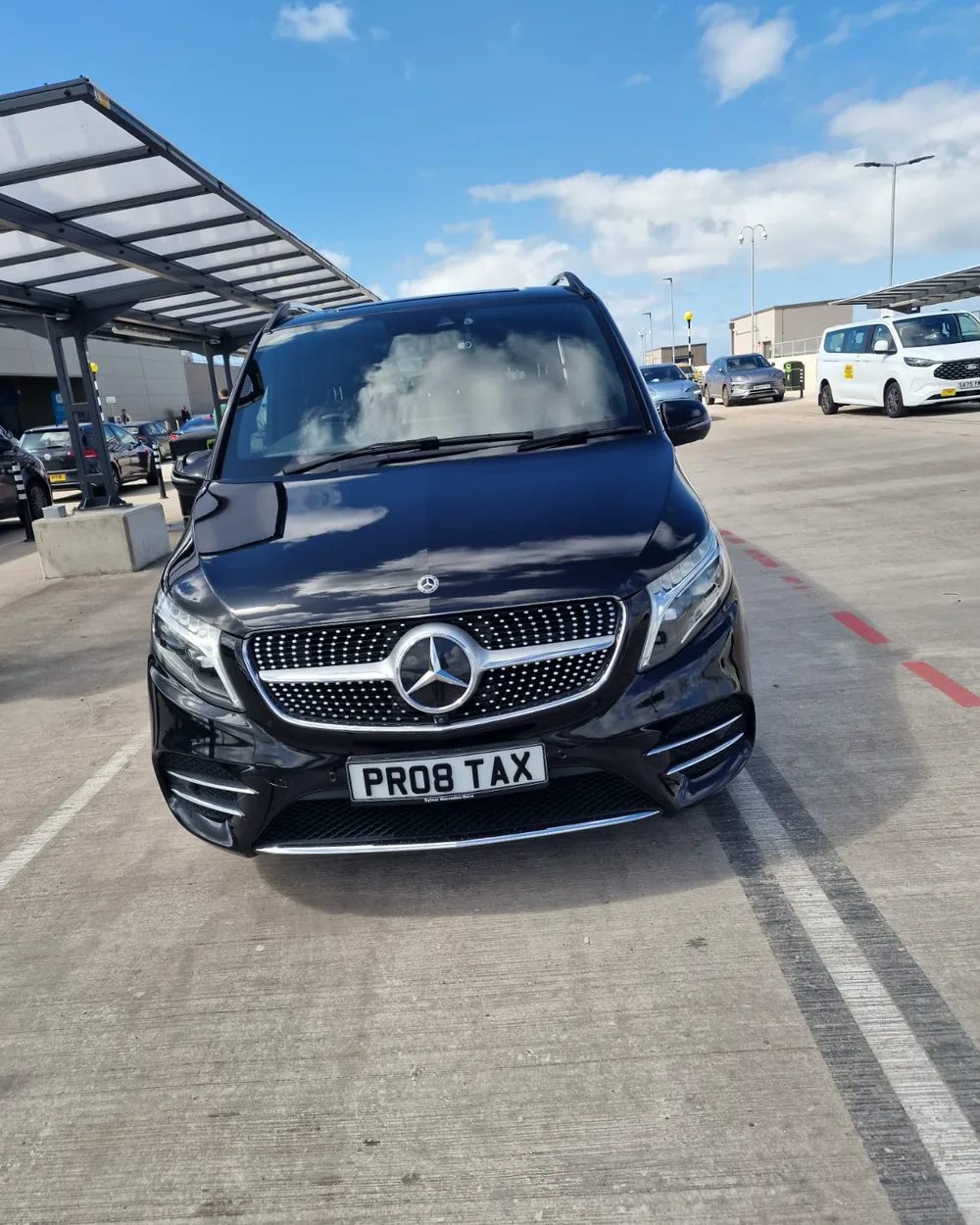 Proline black Mercedes-Benz V-Class waiting at the airport pick-up area for an executive chauffeur transfer